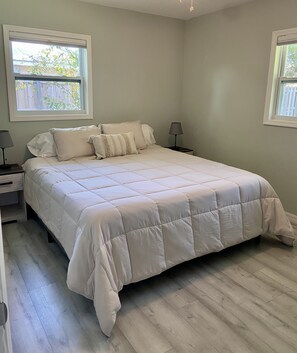 Un dormitorio con una cama grande, dos mesitas de noche y una ventana.