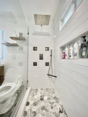 Un baño moderno con ducha, inodoro y suelo de mármol.