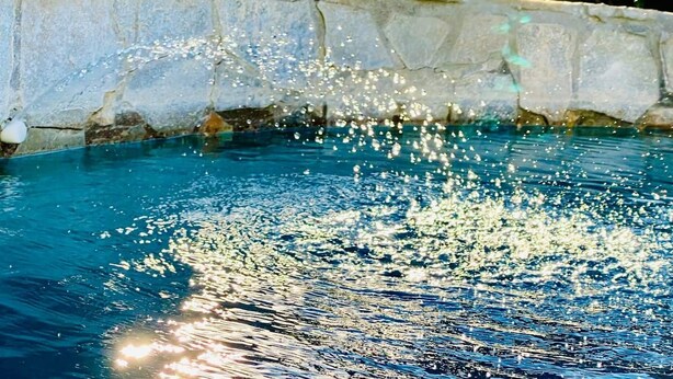 A clear blue pool with water splashing over a stone edge. - Palm Springs Oasis! Private, spacious, pool, spa, sauna shower! (Palm Springs)