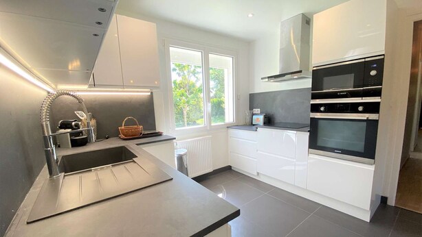 Una cocina moderna con armarios blancos, un lavamanos de acero inoxidable y un horno Bosch.