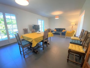A dining area with a table and chairs, a sofa, and a television.