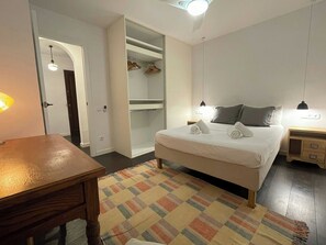 Un dormitorio con cama, mesitas de noche, armario y escritorio.