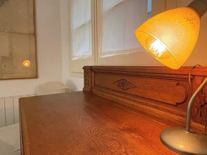 Un escritorio de madera con una lámpara, un radiador y una ventana con persianas.