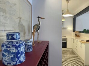 Una cocina con armarios blancos, piso estampado y un soporte de madera con recipientes de cerámica.
