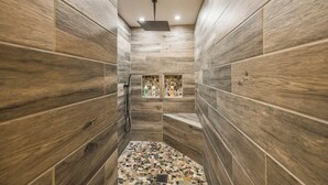 A narrow, tiled shower area with a built-in shelf holding toiletries. - Lynx Lake Luxe Vacation Rental Wrapped in Modern Elegance | 6-BR House , Prescott | Sleeps 22 • Hot Tub • Game Rm • EV Charger • Horse Stalls (Prescott)