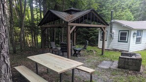 A wooden gazebo with a table and benches in a forested area. - Private, Cozy Cottage in the woods (Indian Lake)
