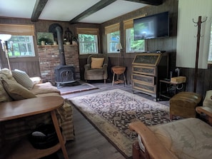 A cozy living room with a fireplace, comfortable seating, a television, and a wooden dresser.
