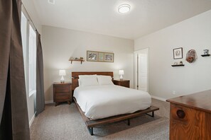 A bedroom with a wooden bed, bedside tables, a nightstand, a dresser, and a door.