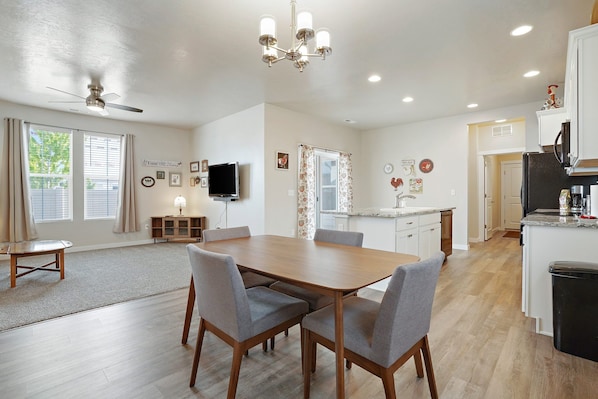 A spacious kitchen with a dining area, wooden flooring, and a ceiling fan.