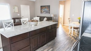 Une cuisine spacieuse dotée d’un grand îlot central, de meubles en bois foncé et d’un plan de travail en marbre.