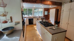 Une cuisine moderne avec des meubles en bois, un îlot central et une vue sur l’extérieur.