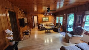 Un intérieur en bois avec un canapé, des fauteuils et un téléviseur.