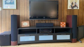 Un salon moderne avec un téléviseur à écran plat fixé à un mur en bois, de part et d’autre duquel se trouvent des haut-parleurs et un meuble multimédia.