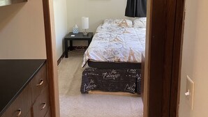 Une chambre à coucher avec un lit, une table de chevet, un tableau encadré et une armoire.