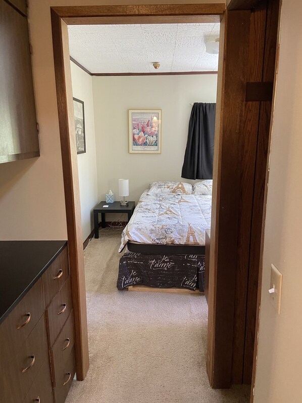 Een slaapkamer met een bed, nachtkastje, een lijst met foto en een garderobe.