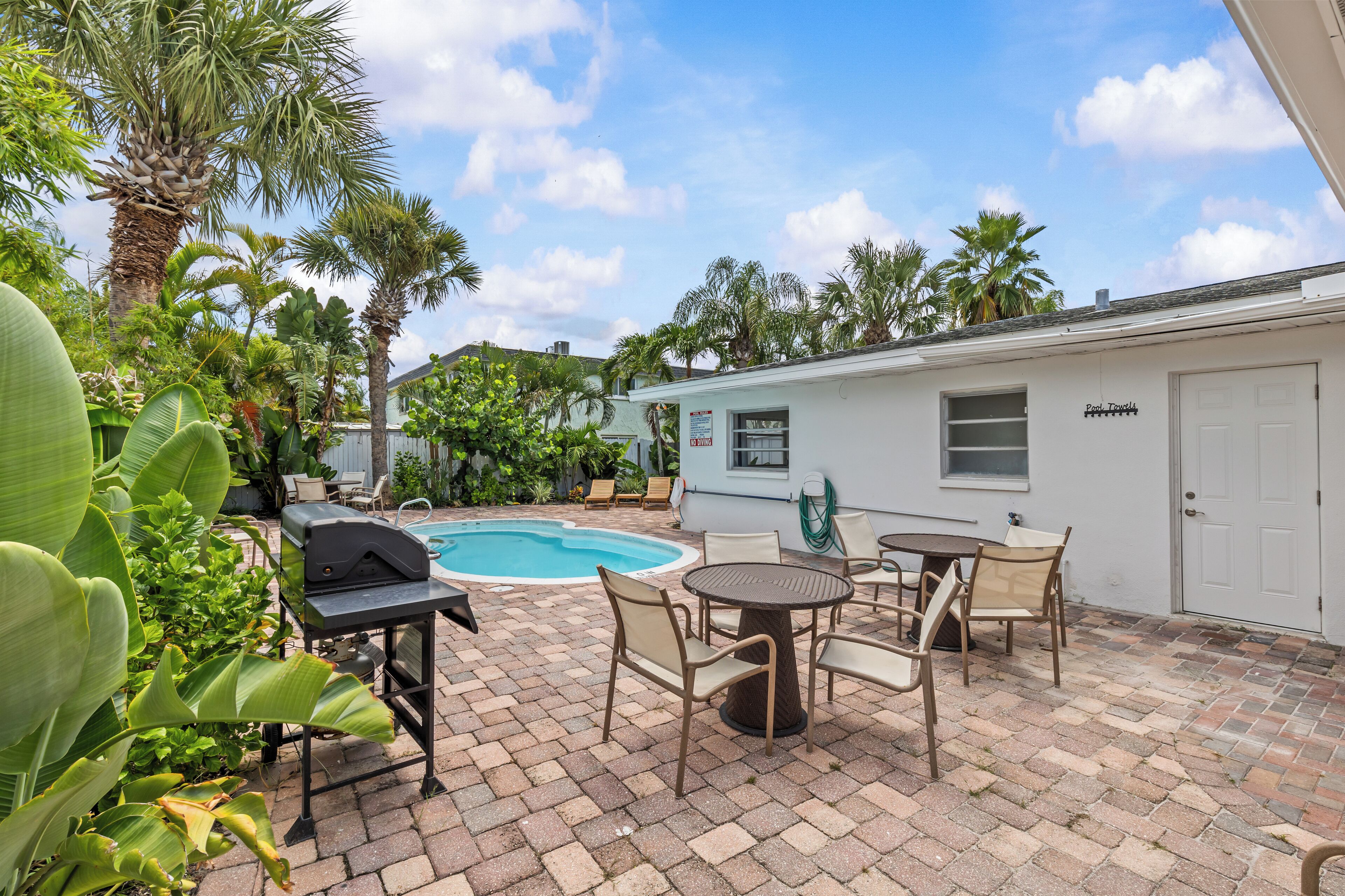 A backyard with a swimming pool, patio furniture, and a barbecue grill.