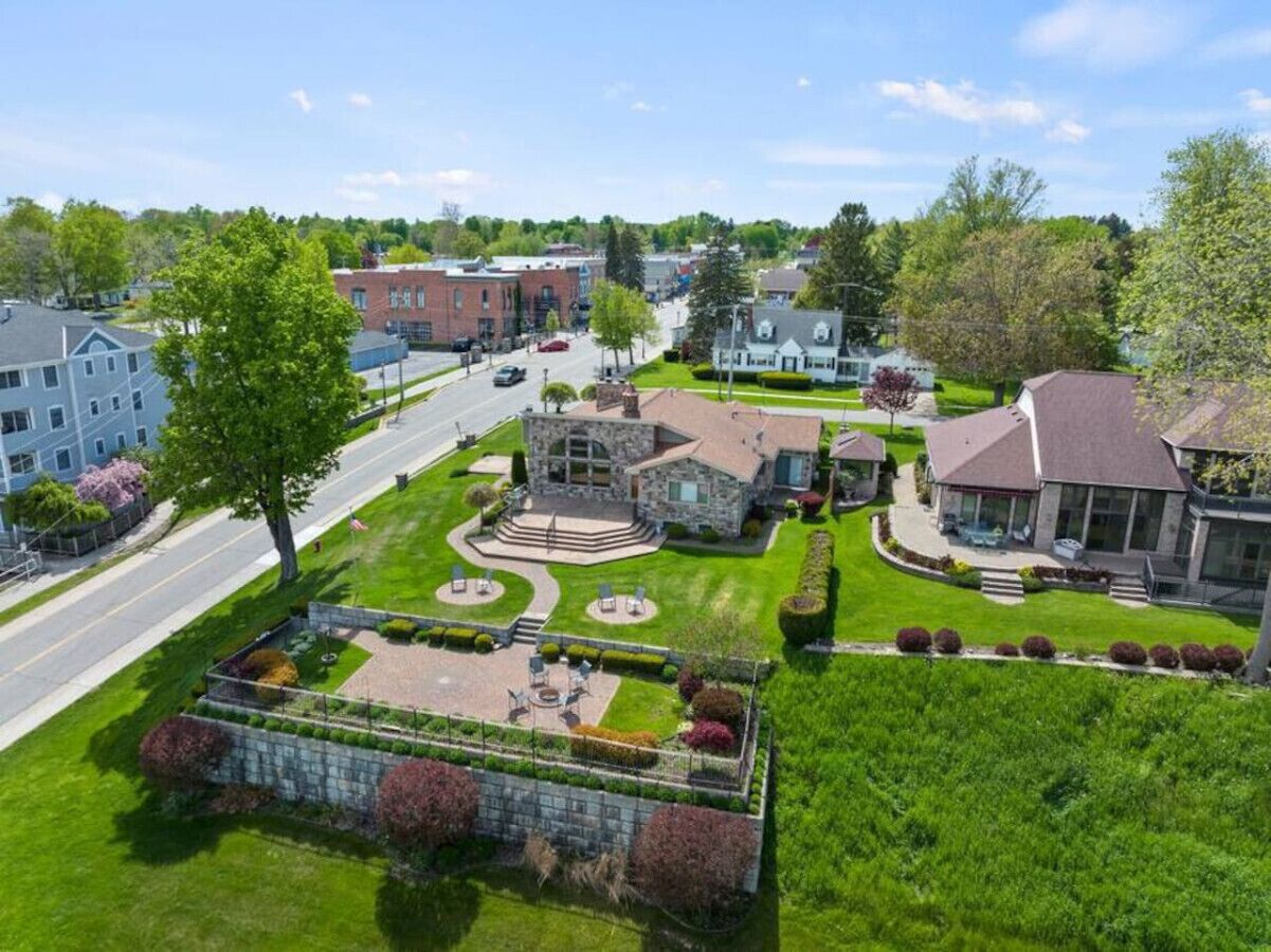 A residential area with a stone house, a well-maintained lawn, and a road in the background.