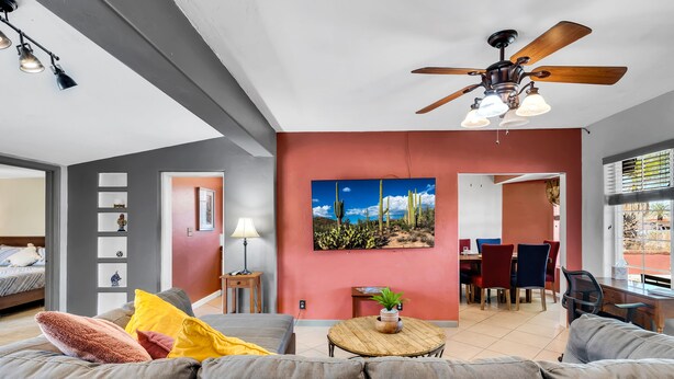 A modern living room with a gray sofa, a wooden coffee table, and a ceiling fan.