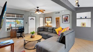 A modern living room with a gray sectional sofa, a wooden coffee table, and a ceiling fan.