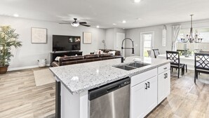 A modern kitchen with granite countertops, stainless steel appliances, and a dining area with a chandelier. - Modern & Cozy ☀ Close to Beach ☀ 4 Bedrooms ☀ 2 Full Baths (Foley)