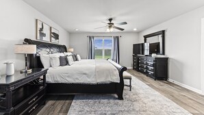 A bedroom with a bed, bedside tables, a dresser, a mirror, and a ceiling fan. - Modern & Cozy ☀ Close to Beach ☀ 4 Bedrooms ☀ 2 Full Baths (Foley)