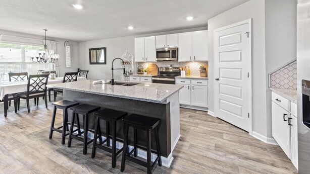 A modern kitchen with white cabinets, a large island with bar stools, a built-in oven, and a microwave. - Modern & Cozy ☀ Close to Beach ☀ 4 Bedrooms ☀ 2 Full Baths (Foley)