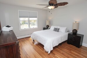 A bedroom with a bed, wooden floor, ceiling fan, bedside lamps, and a window with blinds. - Beach house walking distance to Second Beach (Middletown)