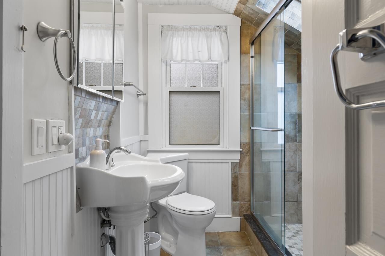 A bathroom with a white sink, toilet, and shower area.