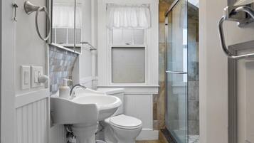 A bathroom with a white sink, toilet, and shower area.