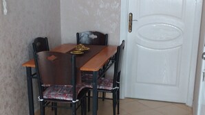 Un coin repas avec une table et des chaises en bois, une porte blanche et un mur à motifs.