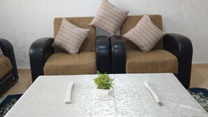 Un salon comprenant un ensemble de canapés, une table basse avec une plante et une petite table sur laquelle est posé un vase.