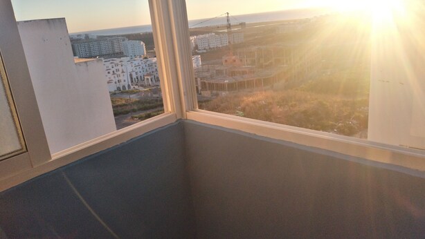 Un balcon offrant une vue sur le paysage urbain au coucher du soleil.