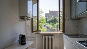 Eine kleine Küche mit Fenster, Heizkörper, Stuhl und Tisch.