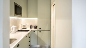 Cocina pequeña con microondas, cafetera y hervidor sobre la encimera.