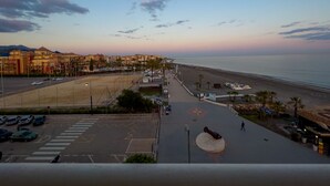 Una veduta costiera con spiaggia, passeggiata e edifici sullo sfondo.