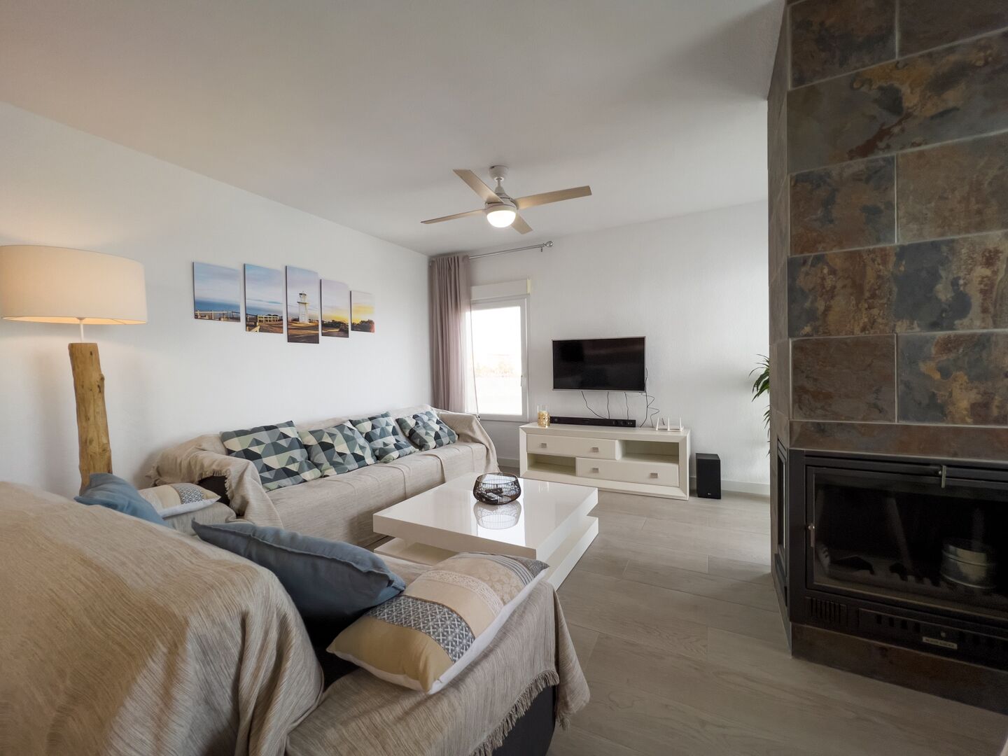 A modern living room with a sofa, coffee table, TV, fireplace, and artwork on the wall.