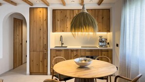 Cozinha moderna com armários de madeira, mesa de jantar redonda e luminária pendente.