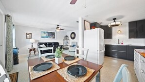 Een moderne keuken met donkere kastjes, een witte koelkast en een eethoek met een houten tafel gedekt voor vier personen.