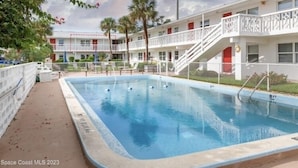 Een motel met een zwembad, een omheind terras en een twee verdiepingen tellend gebouw met balkons.