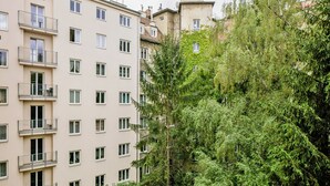 Un edificio residencial de varios pisos con balcones y un árbol verde frondoso en primer plano.