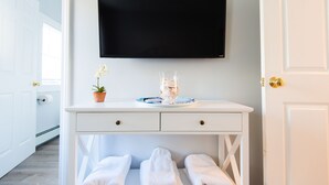 Ein weißer Waschtisch mit Fernseher, einer Topfpflanze und einer Glasvase mit blauem Teller.