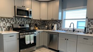 A modern kitchen with grey cabinets, a stainless steel stove, a microwave, and a dishwasher.