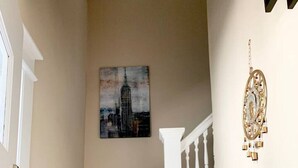 A staircase with carpeted steps, a white railing, and a painting of a building on the wall.