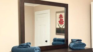 A bathroom vanity with a large mirror, two towels, and a framed artwork on the wall.