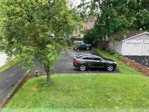 A residential driveway with two cars parked, a tree, and a garage.