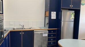 A compact kitchen with a stainless steel refrigerator, a dishwasher, and a sink with a faucet.