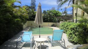 A pool area with a lounge chair, a table, and an umbrella. - Sea Eagles 10 Steps To Kings & Shelly Beach (KINGS BEACH)