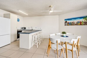 A modern kitchen with a central island, white cabinetry, a microwave, and a clock. - Edmund Shores 6 Walk To Kings Beach, Ocean Views (KINGS BEACH)