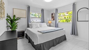 Une chambre moderne avec un lit, une table de chevet, une lampe et une grande fenêtre avec des rideaux.
