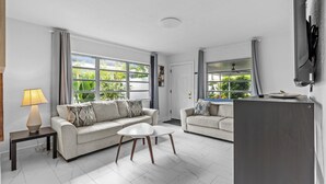 Un salon moderne avec deux canapés, une table basse et un téléviseur posé sur un meuble.